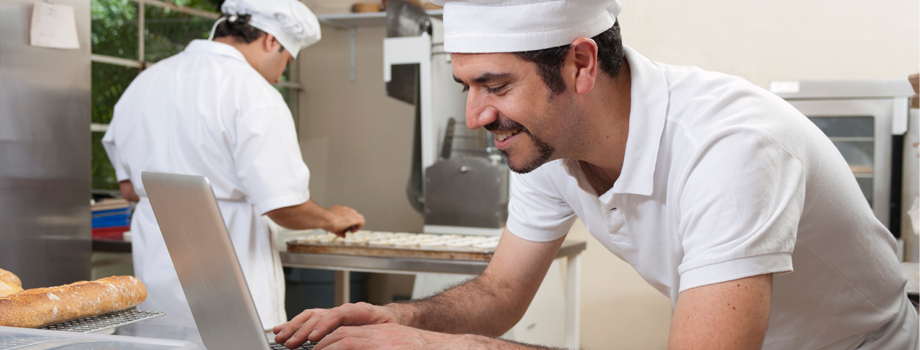 Chef leaning at table at computer